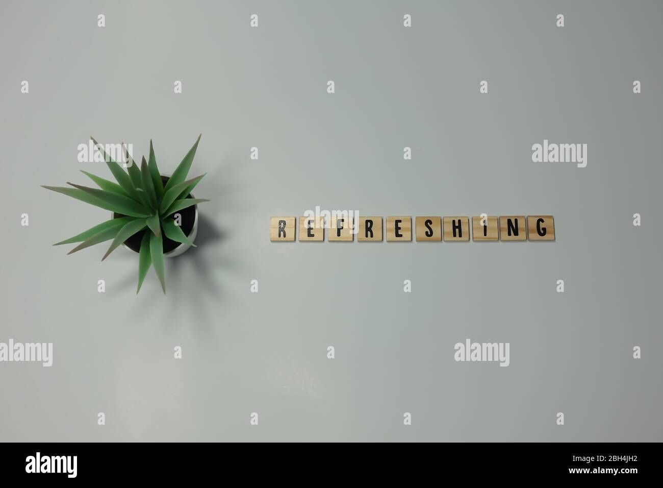 Das Wort erfrischend geschrieben in hölzernen Buchstabenfliesen auf weißem Hintergrund. Stockfoto