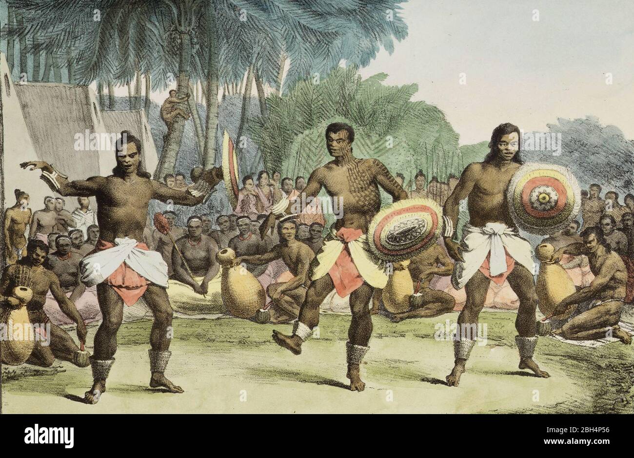 Drei hawaiianische Männer tanzen, umgeben von einem Ring von Zuschauern, mehrere halten Trommeln. Im Hintergrund sind Kokospalmen und die Seiten mehrerer Wohnungen zu sehen. Die Tänzer tragen Röcke und Fußknöchel und halten Schilde - Louis Choris, 1816 Stockfoto