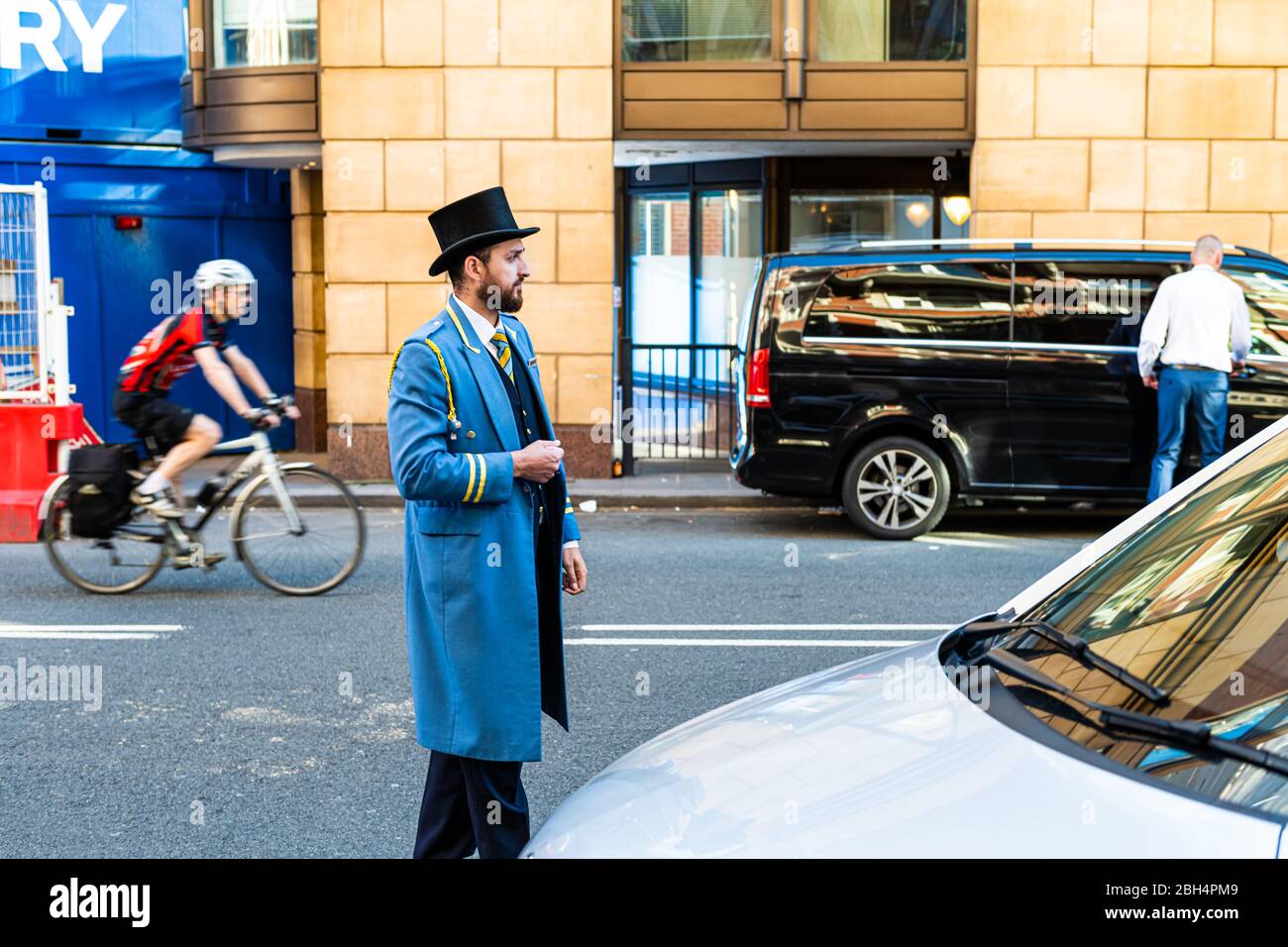 London, Großbritannien - 22. Juni 2018: Portier Portier in traditioneller Kleidung Hut und blauen Mantel stehen am Hoteleingang mit dem Auto hilft mit Gepäck Stockfoto