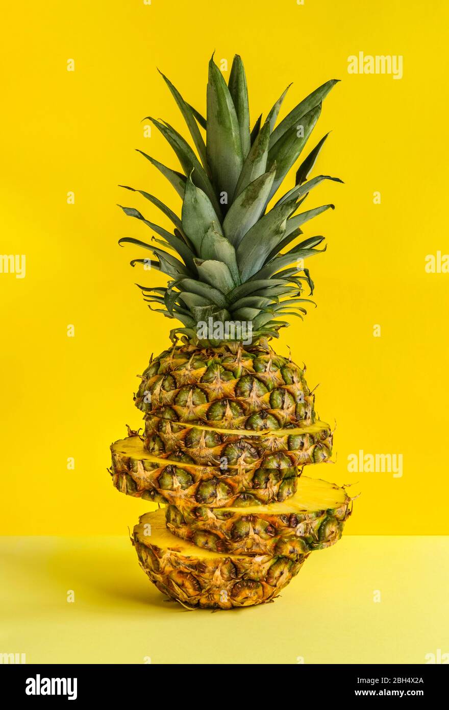 Ananas auf gelbem Hintergrund in Scheiben geschnitten Stockfoto