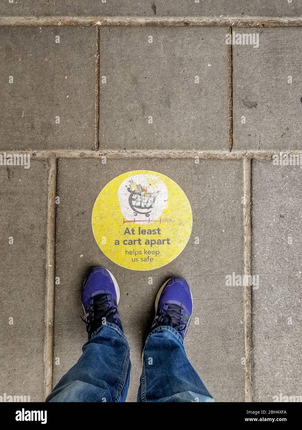 Zumindest ein Karren auseinander, soziales Distanzierzeichen vor einem US-Supermarkt, um das während des Corona-Virus pande ein Mann in Tennisschuhen herumsteht Stockfoto