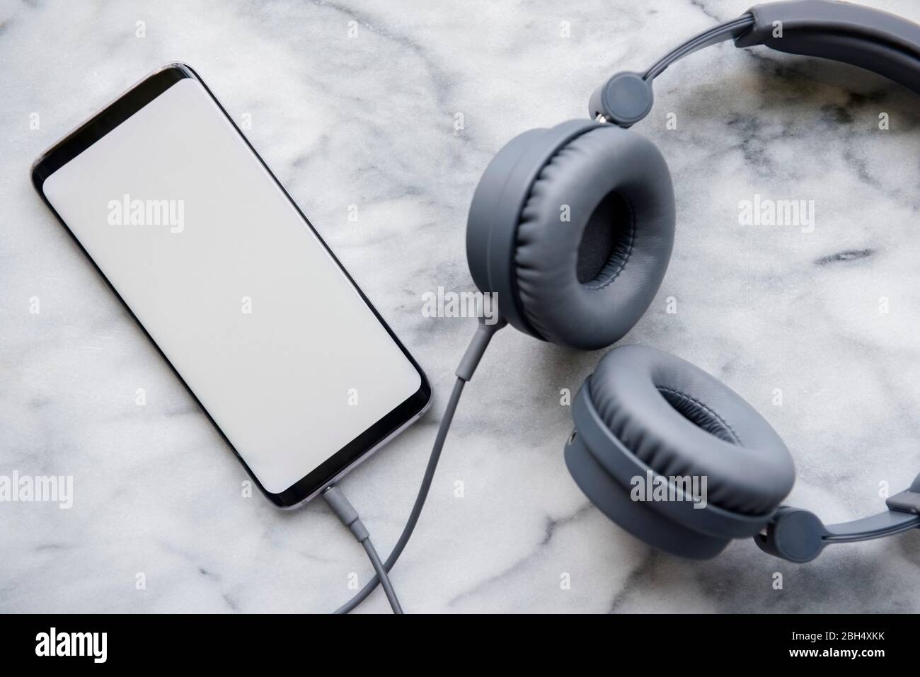 Schwarze Kopfhörer, die mit einem Smartphone verbunden sind Stockfoto