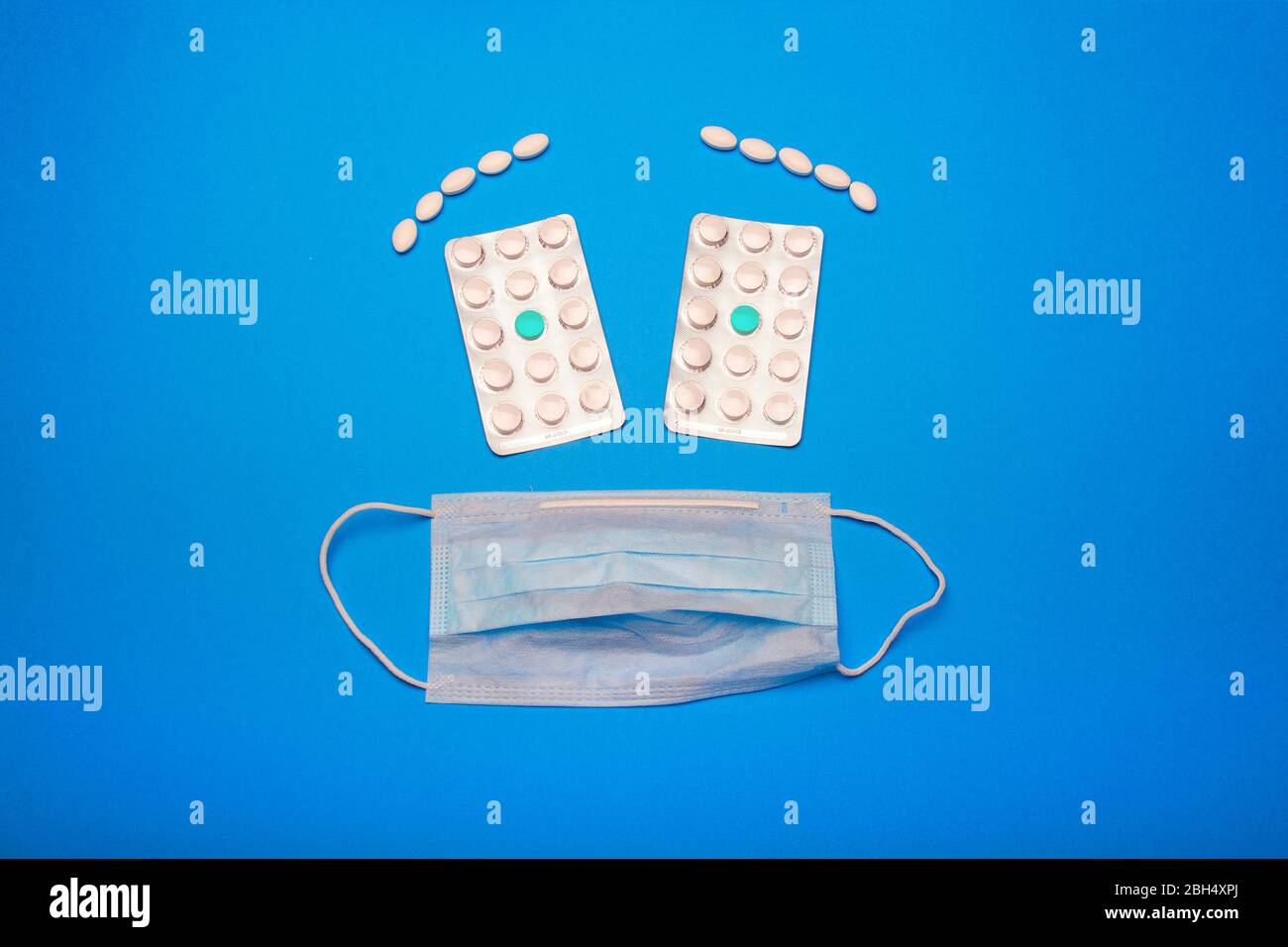 Gesicht einer weißen medizinischen Maske und zwei Blasen von Tabletten Stockfoto