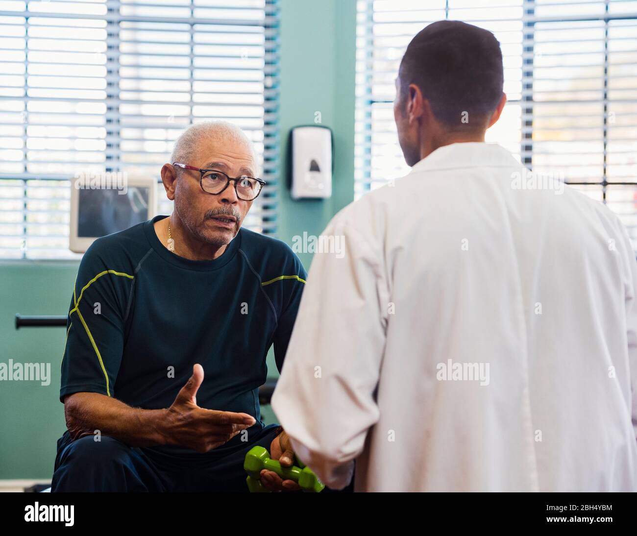 Älterer Mann im Rehabilitationszentrum im Gespräch mit dem Arzt Stockfoto