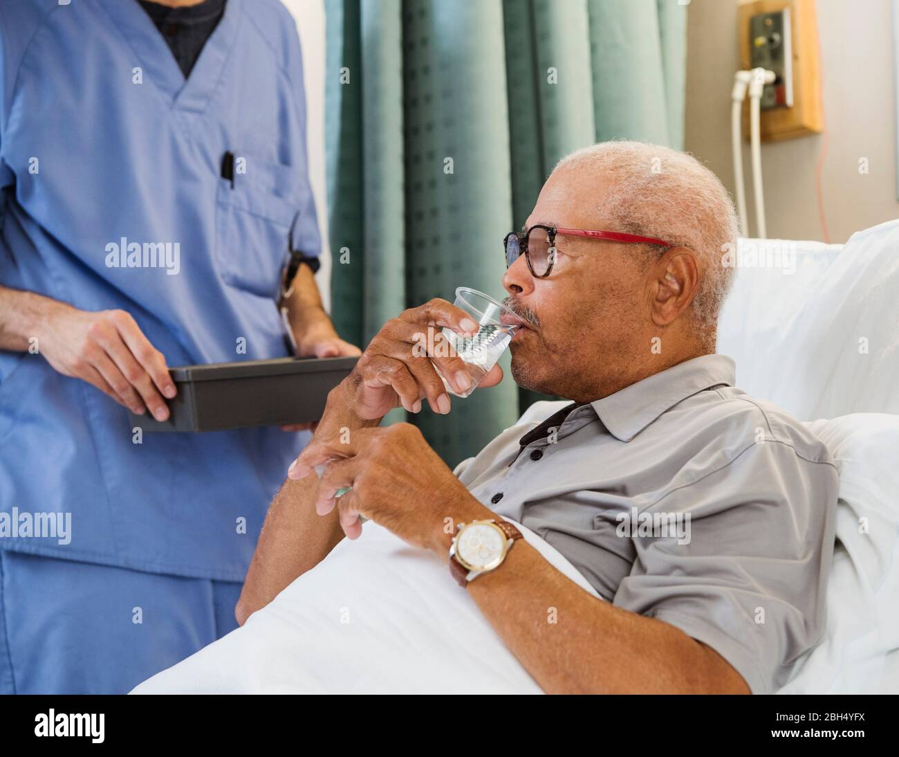 Älterer Mann, der Wasser im Bett trinkt Stockfoto