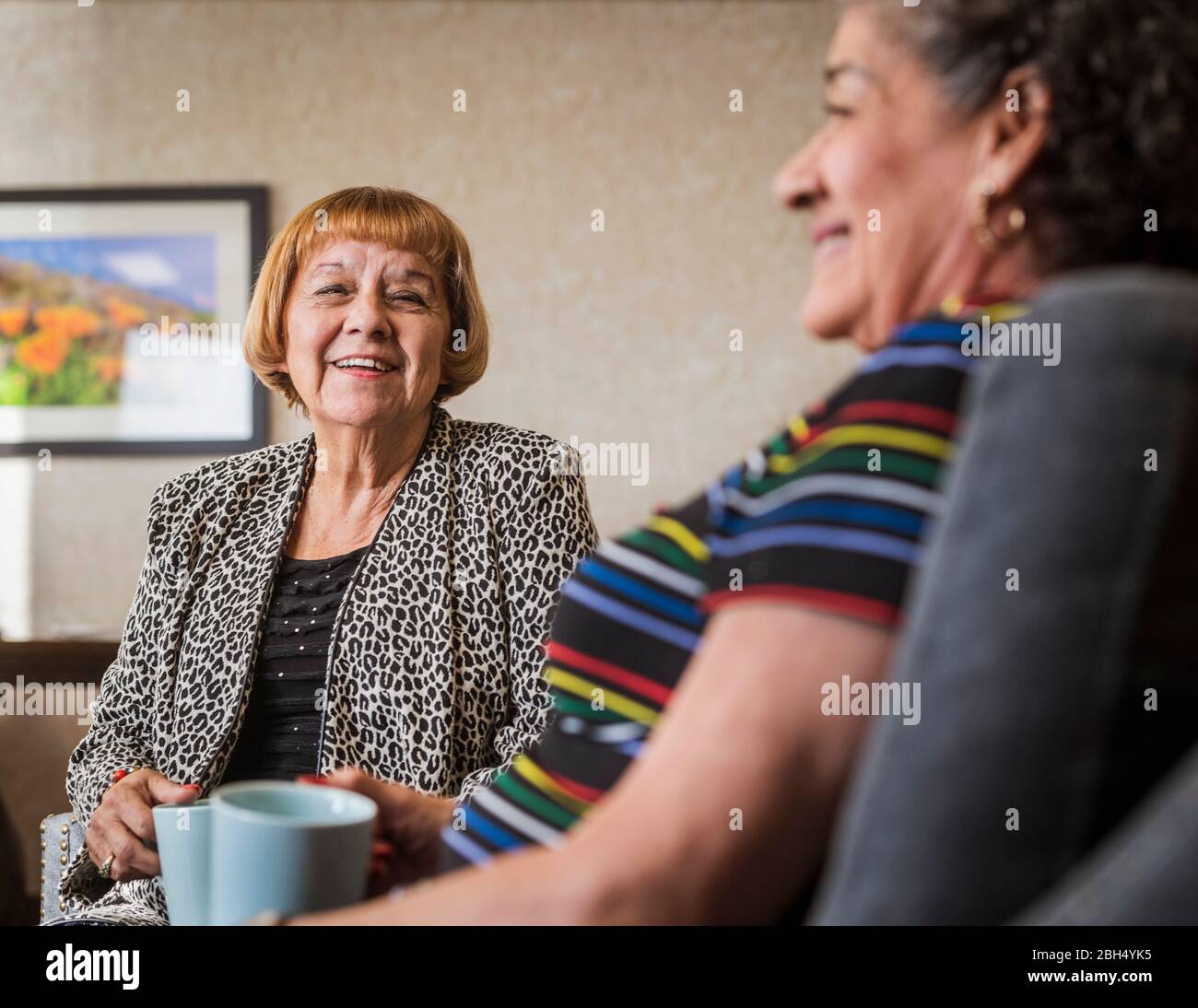 Lächelnde ältere Frauen halten Tassen Stockfoto