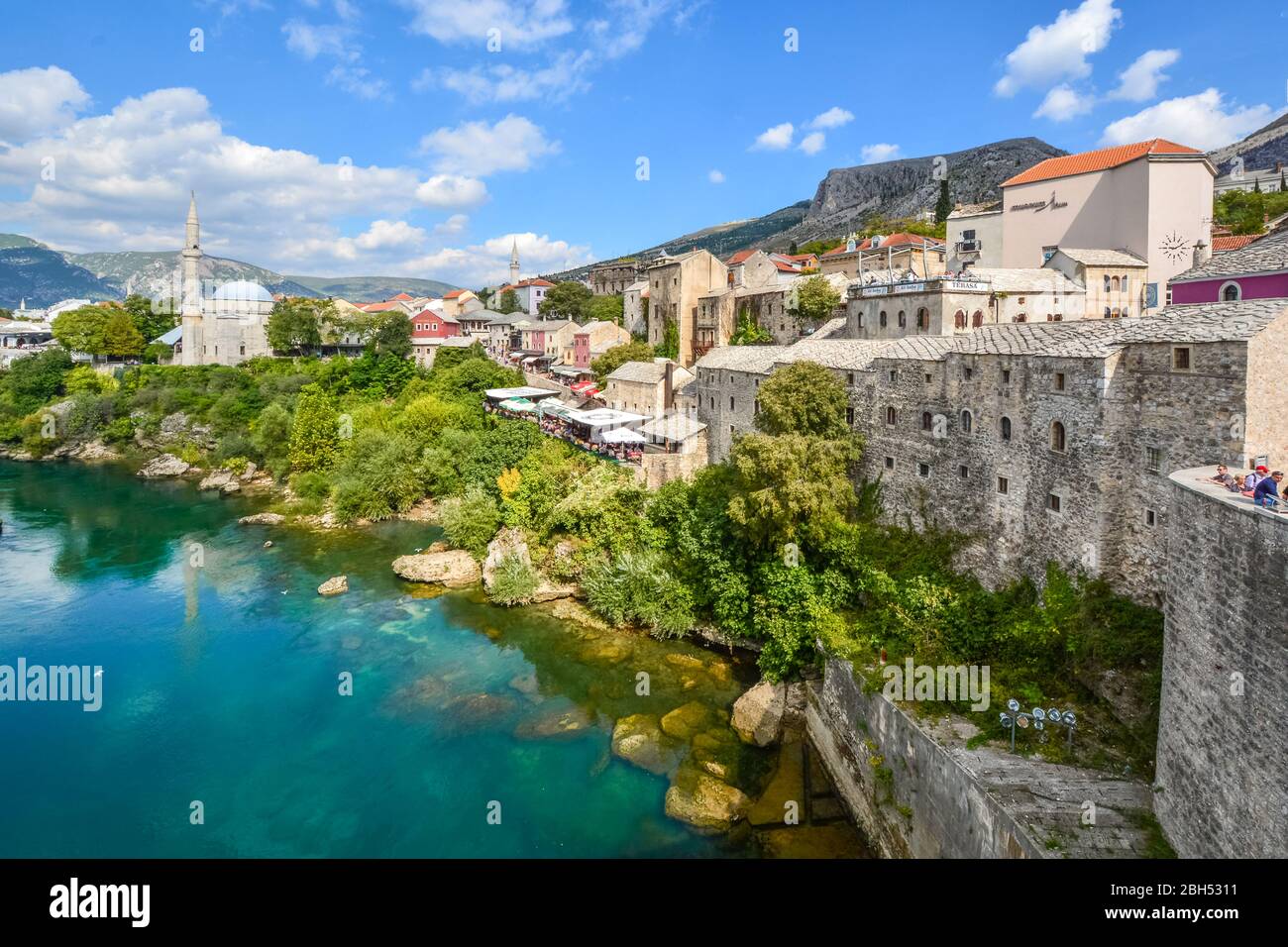 Ein Blick auf die alte Stadt Mostar, Bosnien mit seiner Altstadt, Cafés am Fluss, Minarette und Moscheen von der alten Brücke über den Fluss Neretva genommen. Stockfoto