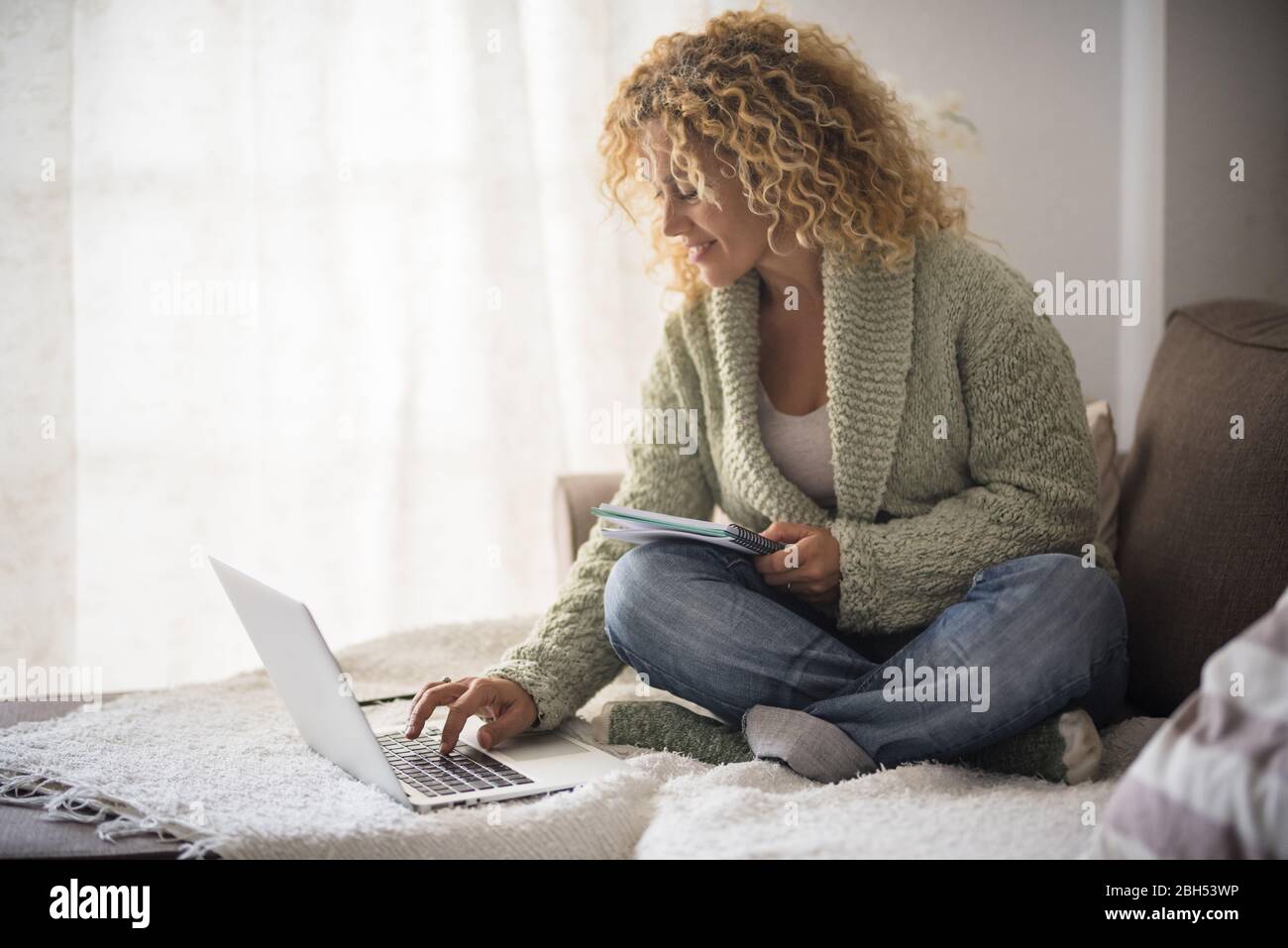 Lächelnde Frau, die mit einem Laptop auf dem Sofa arbeitet Stockfoto