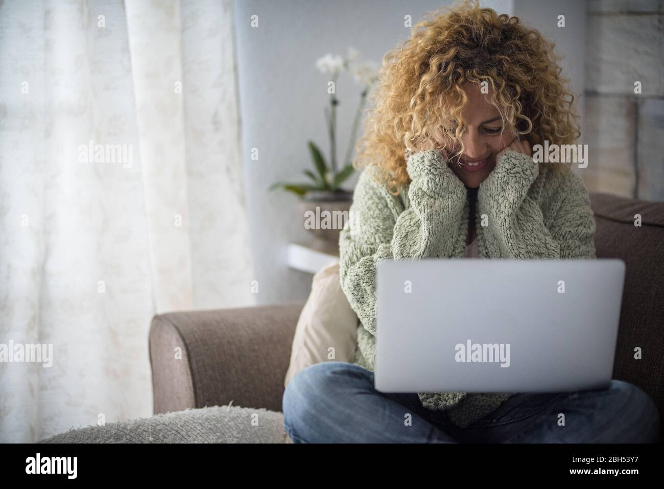 Lächelnde Frau, die mit einem Laptop auf dem Sofa arbeitet Stockfoto
