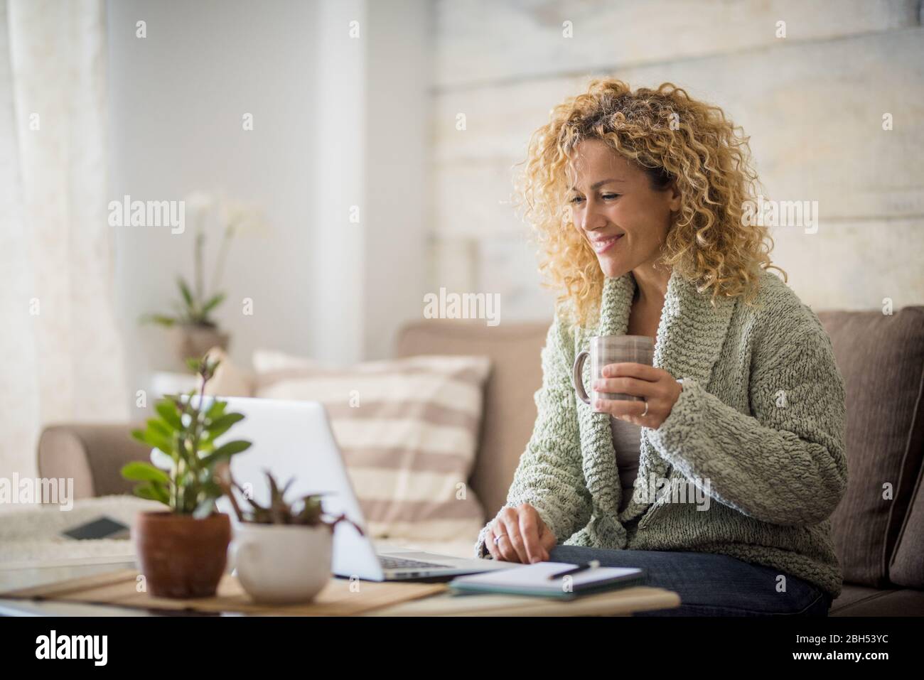 Lächelnde Frau hält einen Drink am Laptop Stockfoto