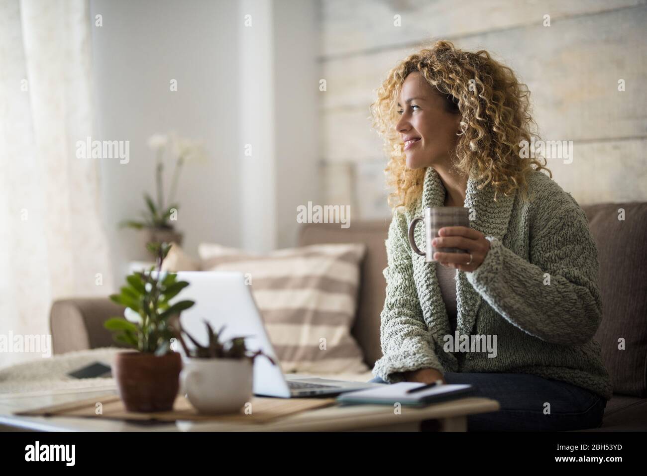 Lächelnde Frau hält einen Drink am Laptop Stockfoto