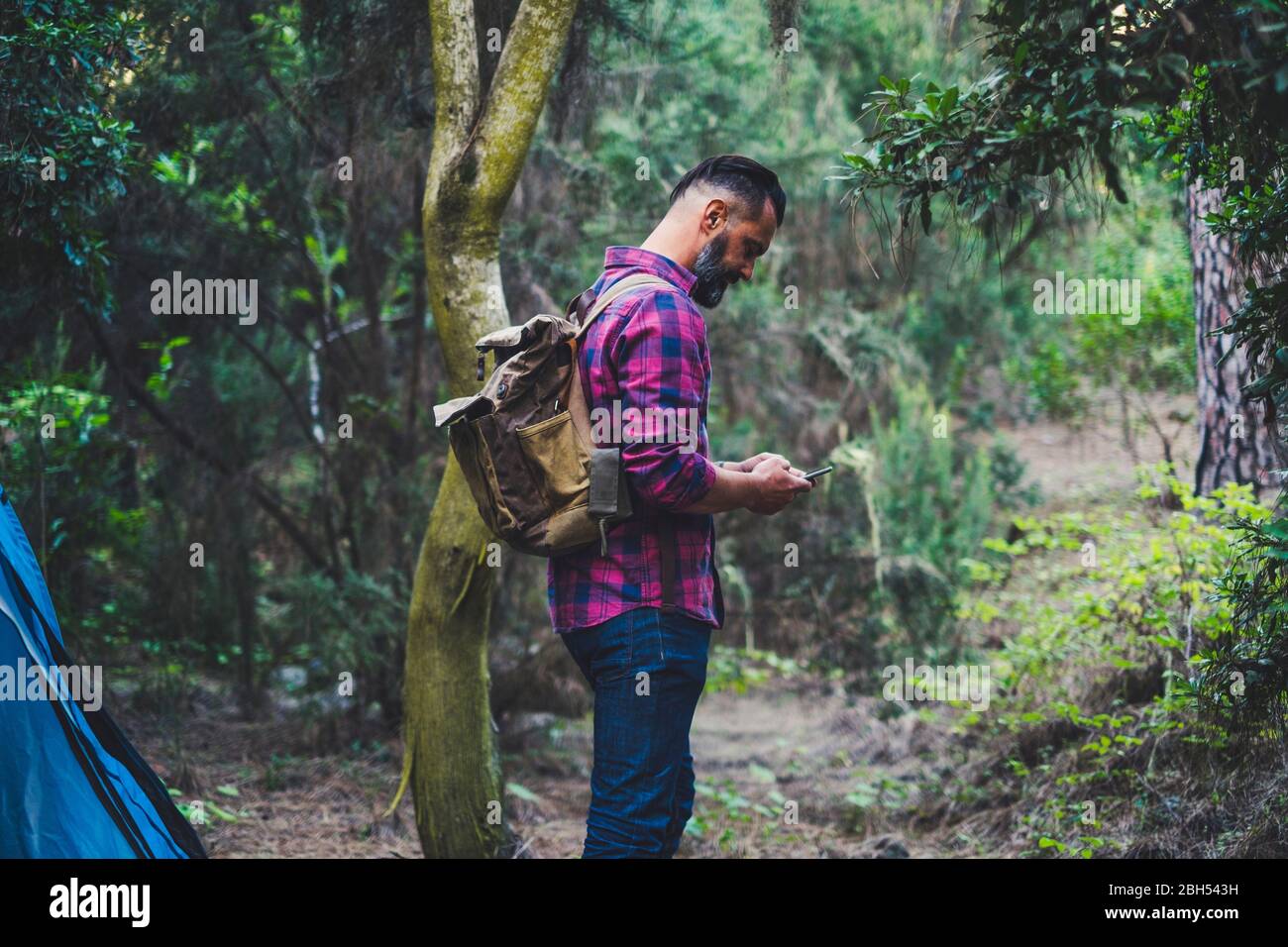Mann trägt Rucksack mit Smartphone im Wald Stockfoto