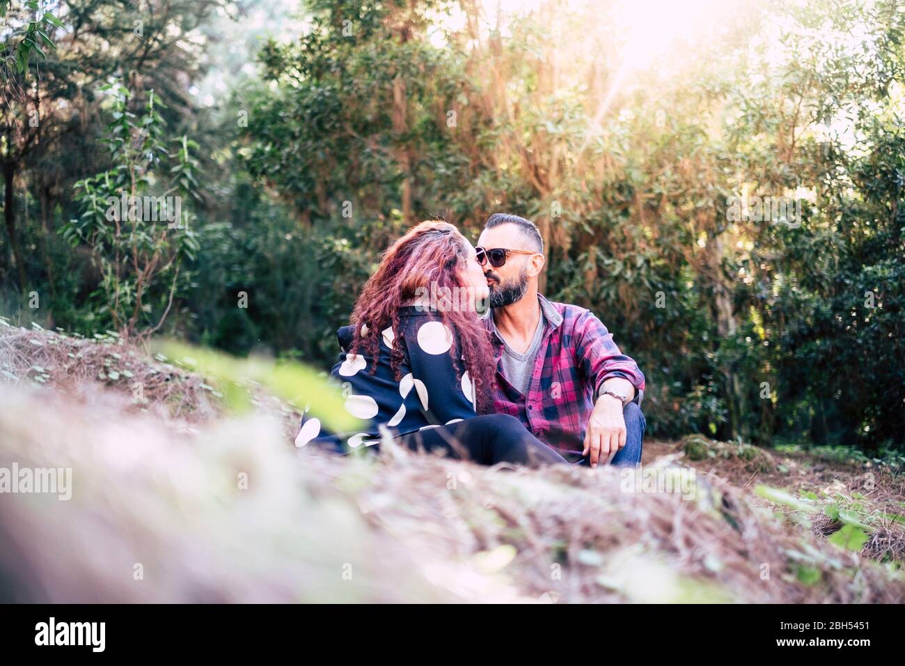 Küssen Paar auf Gras sitzen Stockfoto