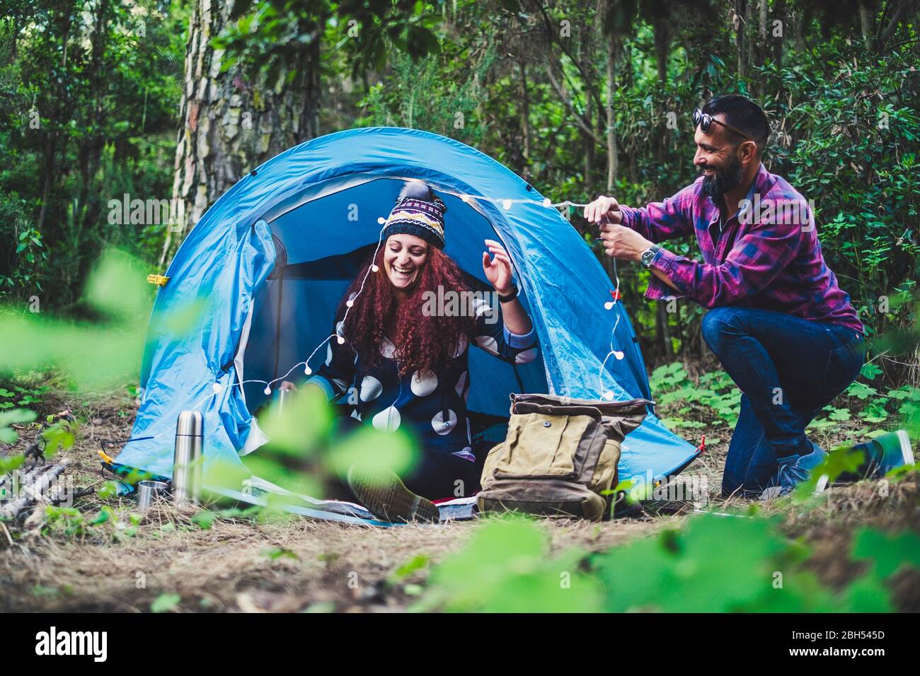 Lächelndes Paar, das Lichterketten auf das Zelt setzt Stockfoto