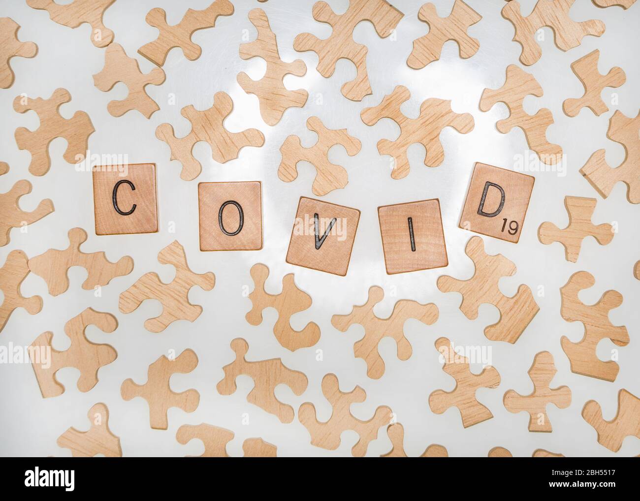 Eine Ansicht von Puzzleteilen, die gekachelte Buchstaben umgeben, die das Wort COVID-19 schreiben. Stockfoto