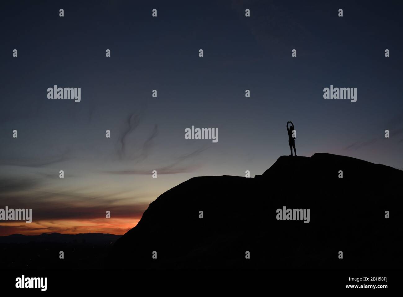 Ein Junge steht auf einem Hügel, während er mit seinem Telefon den Sonnenuntergang in Victoria, British Columbia, Kanada auf Vancouver fotografiert Stockfoto