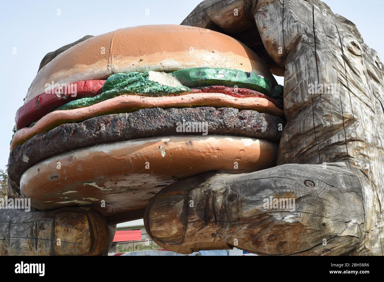 Ein riesiges hölzernes Paar Hände hält ein übergroßes Hamburger-Modell vor dem Dog N' Suds Restaurant in Williams Lake, British Columbia, Kanada Stockfoto
