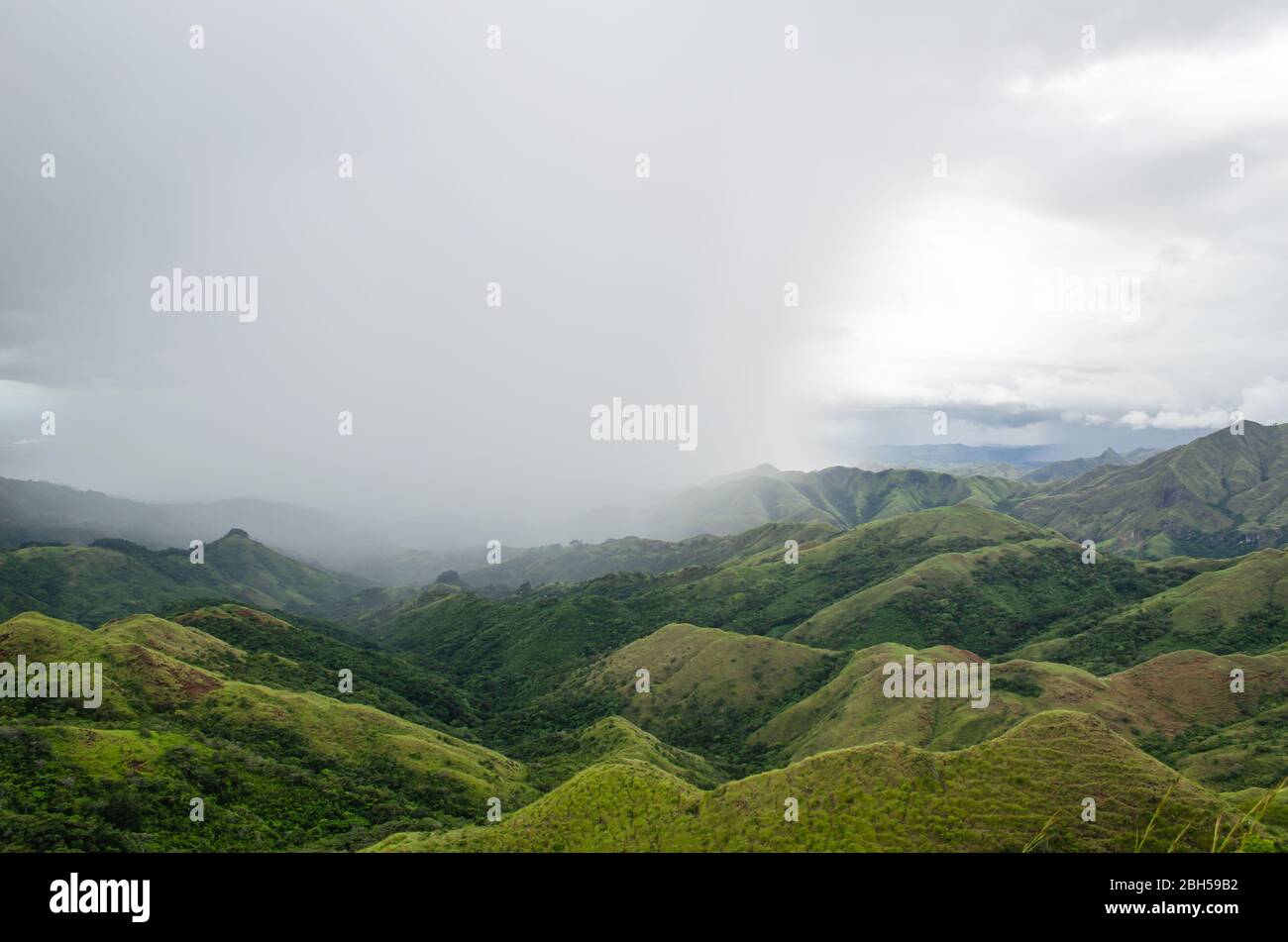 Faszinierende Berglandschaft in Zentral-Panama, mit dichten Wolken, die den Himmel umhüllen und sanftem Regen, der über die grünen Hügel fällt. Stockfoto