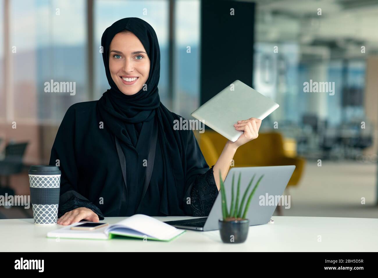 Professionelle junge muslimische Geschäftsfrau mit mobilen digitalen Tablet-Computer bei der Arbeit Stockfoto