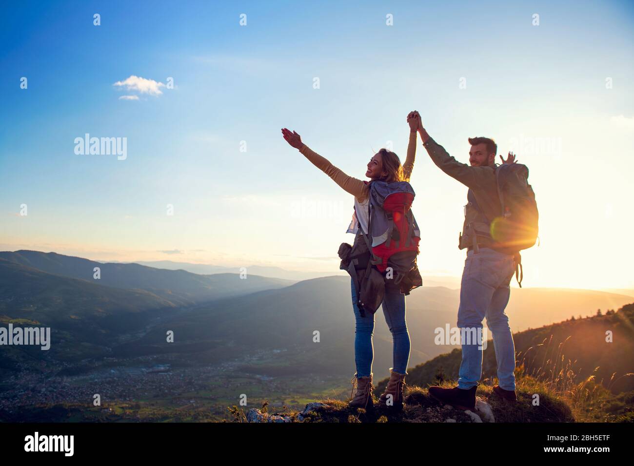 Fröhliche Paar Mann und Frau Touristen auf dem Gipfel des Berges bei Sonnenuntergang im Freien während einer Wanderung im Sommer Stockfoto
