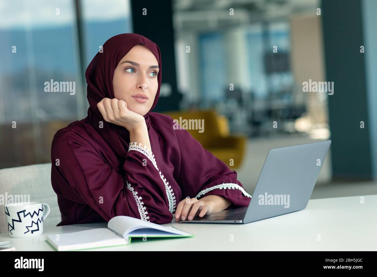 Nachdenkliche arabische Geschäftsfrau, die am Arbeitsplatz im Büro sitzt Stockfoto