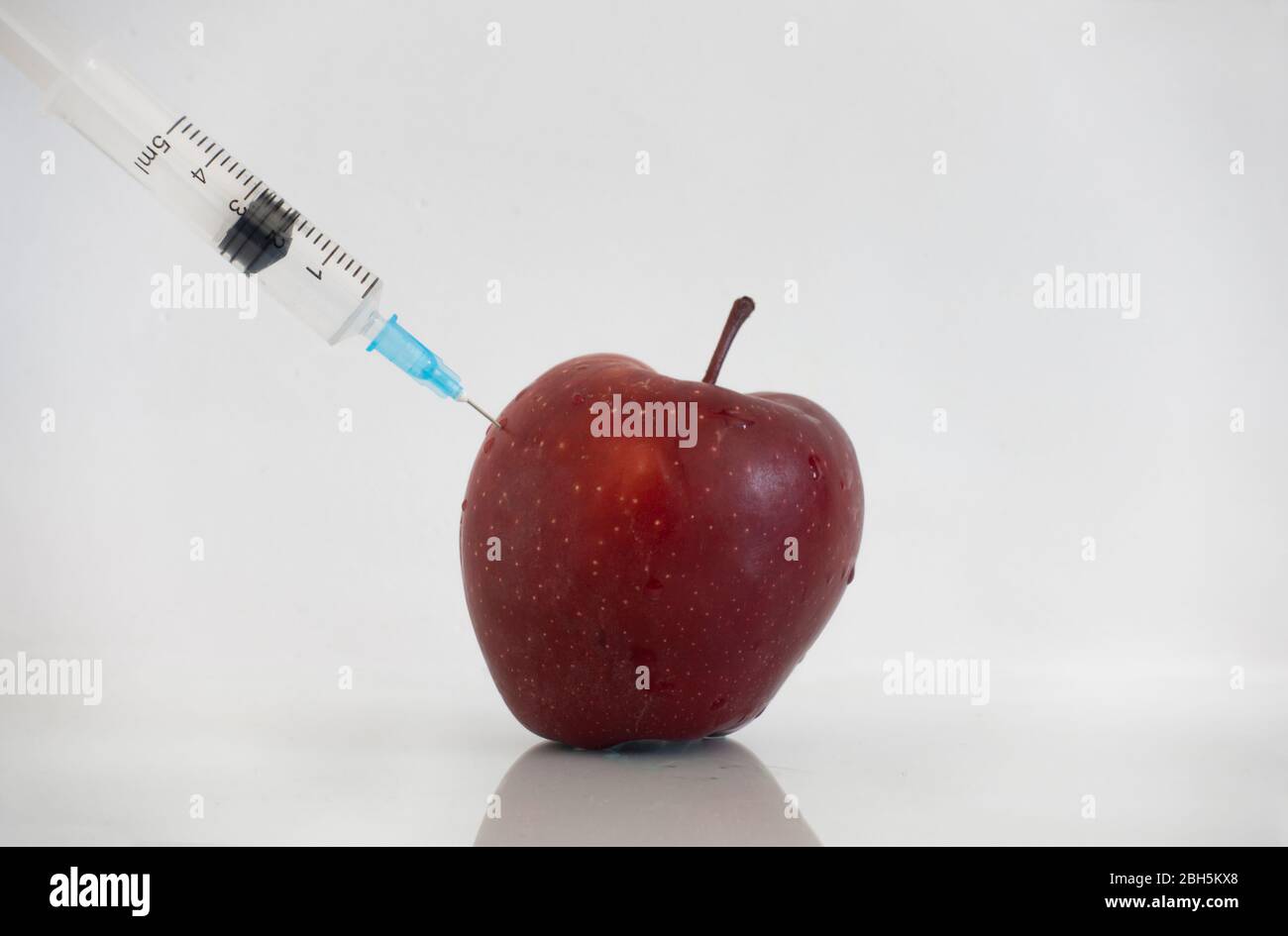 Pestizide und Nitrate werden mit einer Spritze in einen roten Apfel injiziert. GVO-Konzept und genetisch veränderten Organismus. GVO frei und natürliche Früchte mito Stockfoto