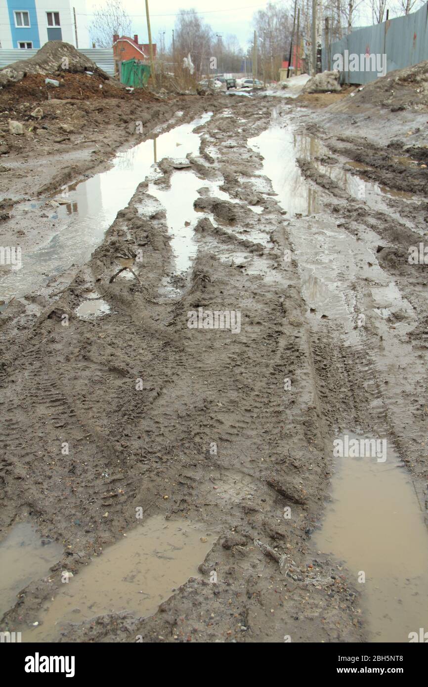 Schmutzige Feldweg mit Spur, Radspuren, brauner Lehm und Pfützen in Russland. Stockfoto