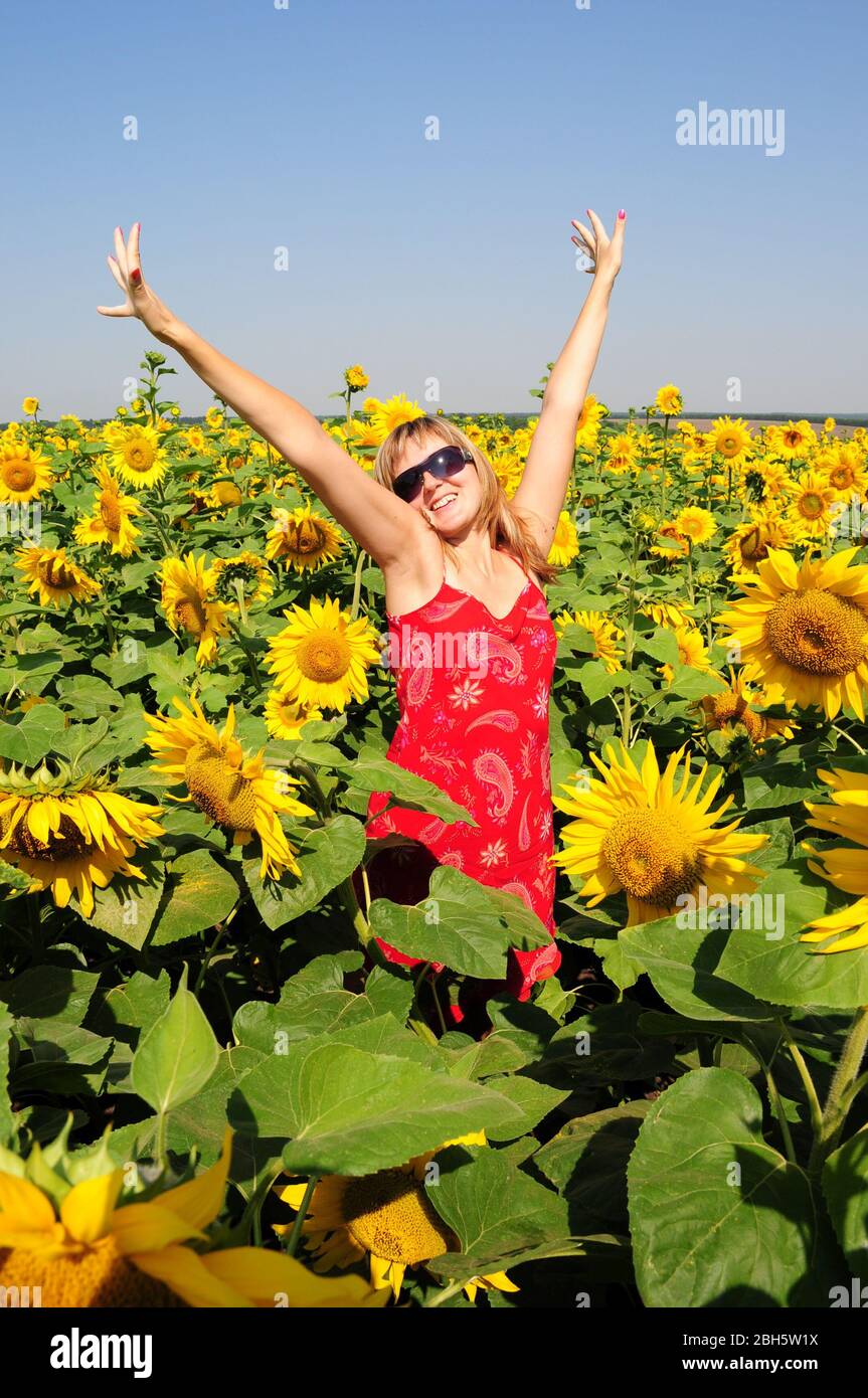 Blonde Haare Frau in Sonnenbrille und rotes Kleid mit gelben Blumen Hintergrund. Sommerstimmung. Stockfoto