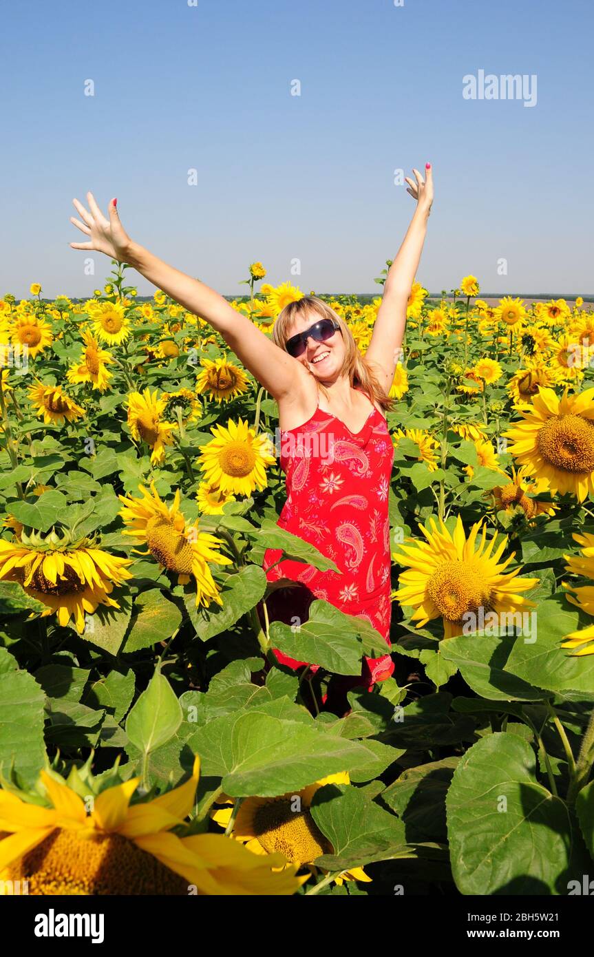 Blonde Haare Frau in Sonnenbrille und rotes Kleid mit gelben Blumen Hintergrund. Sommerstimmung. Stockfoto