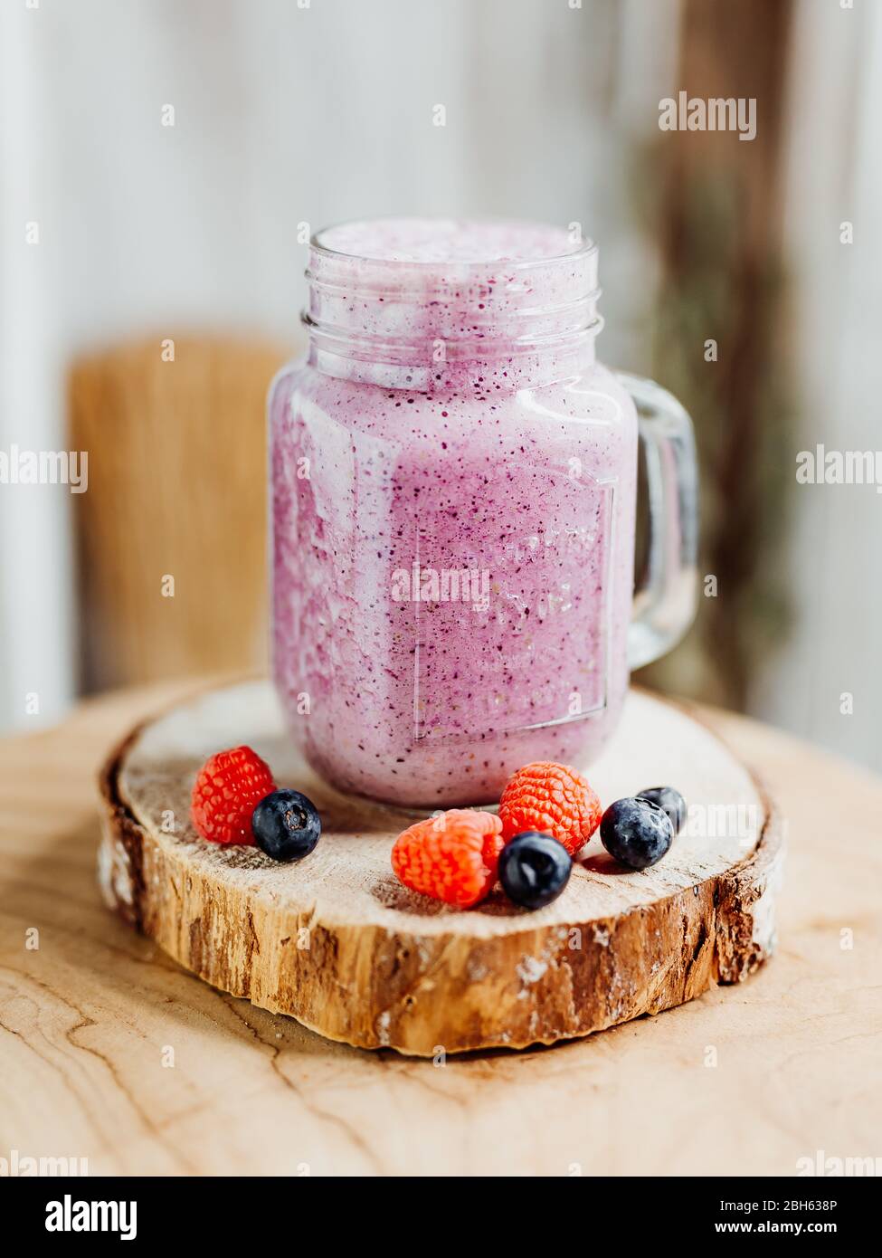 Gesunder Vitaminshake mit Drachenfrucht, Beeren, Chiasamen und Mandelmilch in einem stilvollen Glas, dekoriert mit Himbeere und Heidelbeere Stockfoto