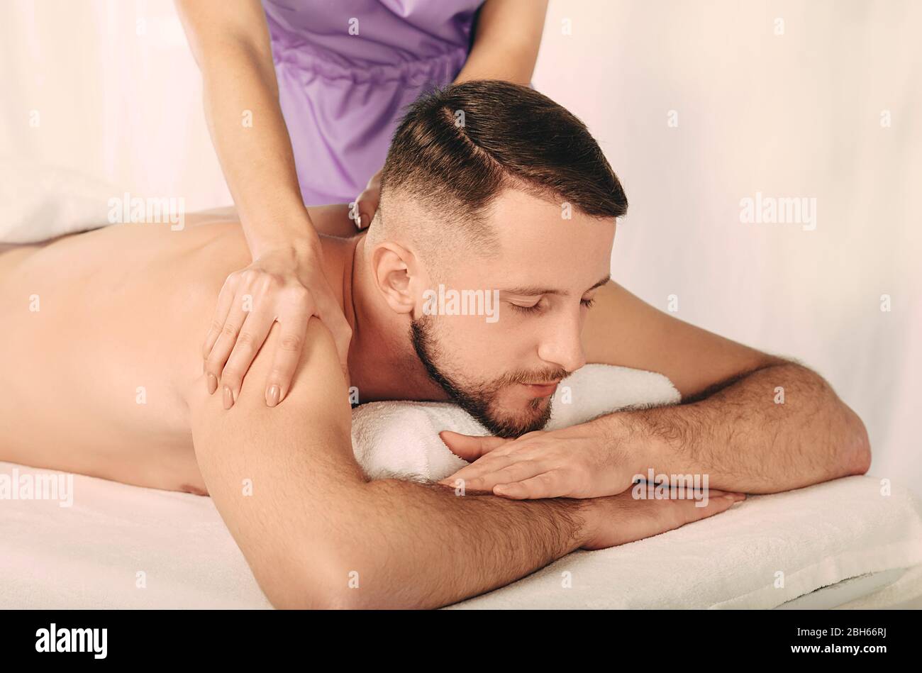 Professionelle Masseur massiert den Rücken des Mannes im Wellness-Center Stockfoto