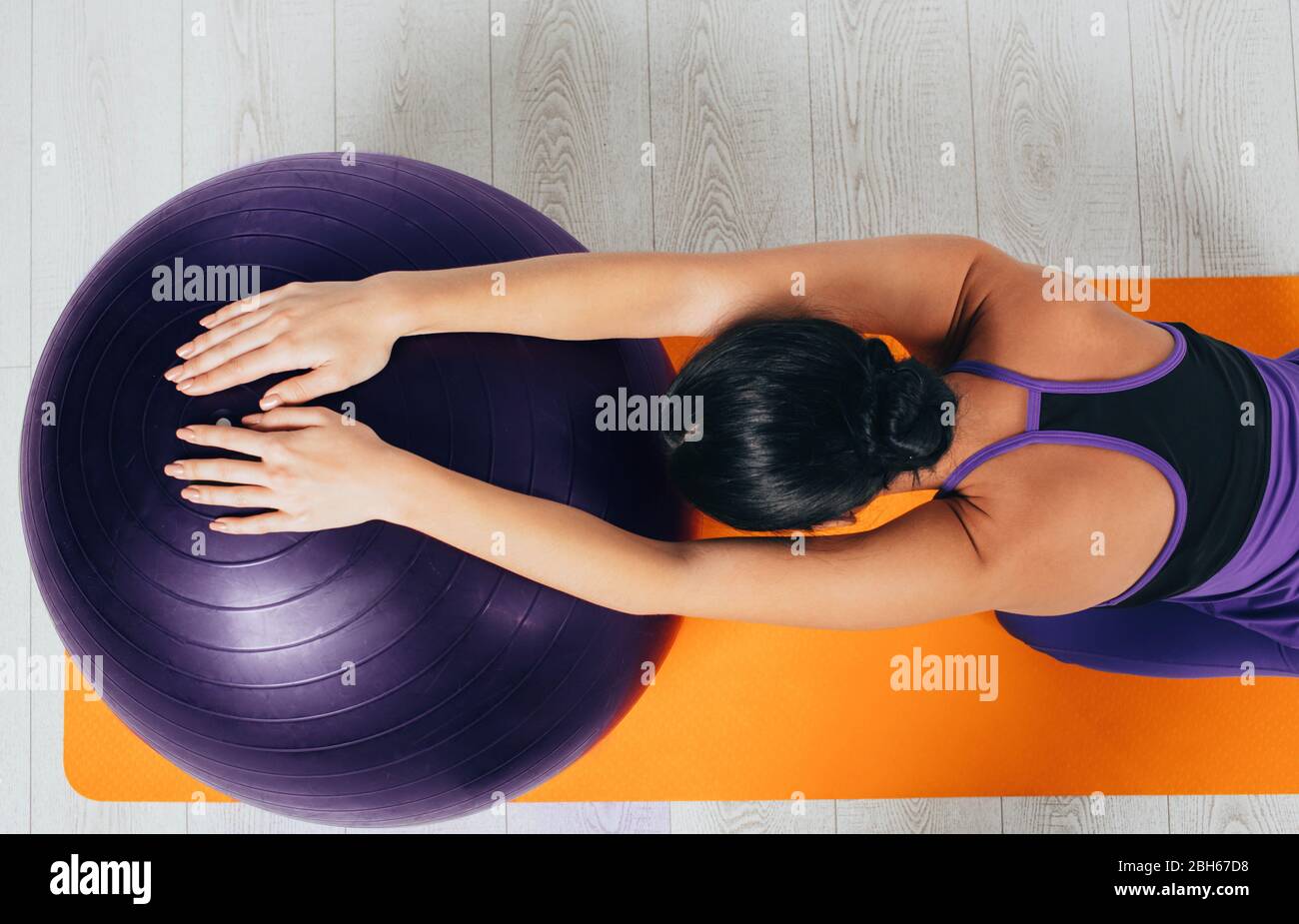 Schlanke Frau Stretching ihren Rücken mit Pilates Ball. Workout zu Hause Stockfoto