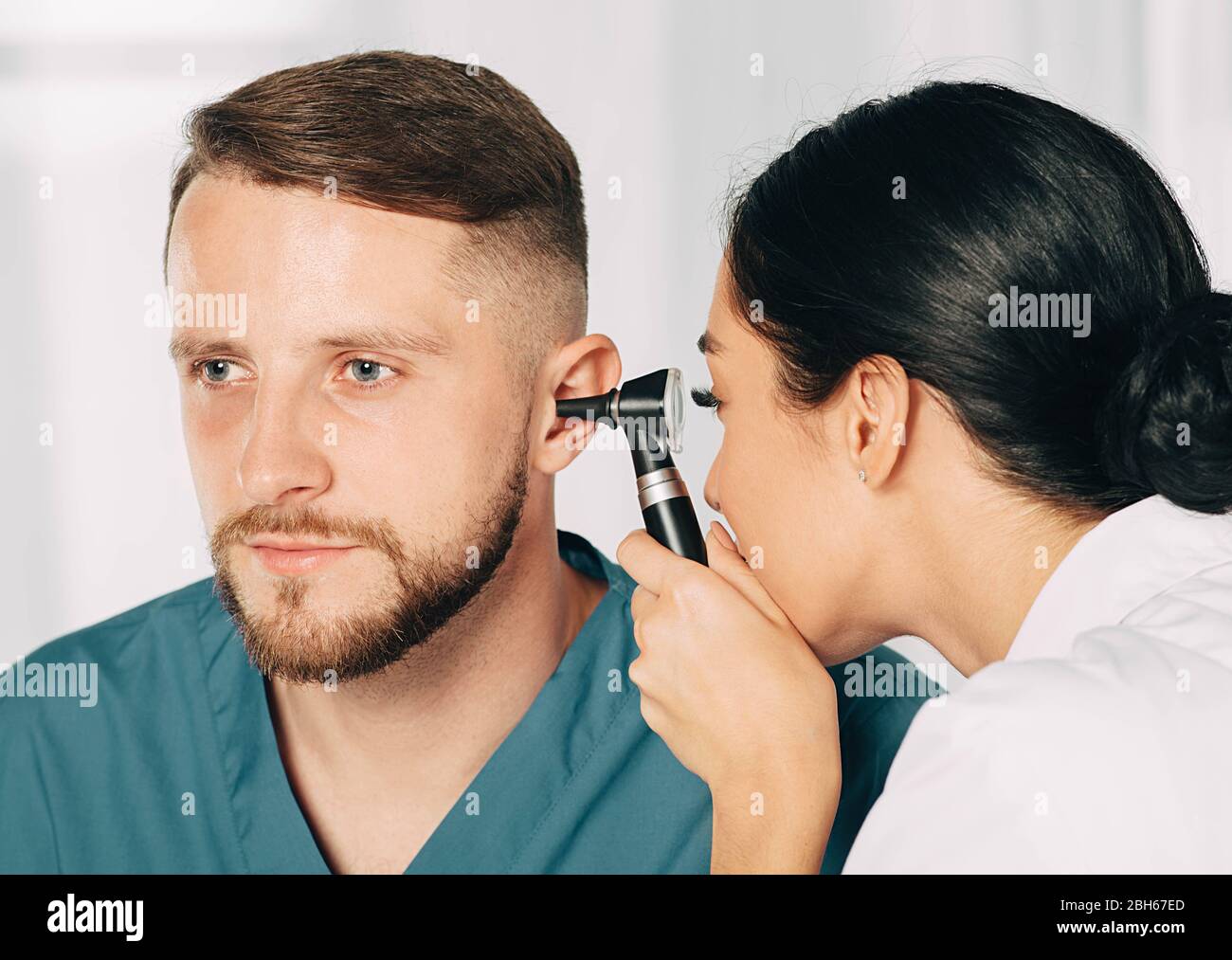 Mann bekommen medizinische Ohr Untersuchung in der Klinik. Audiologe Untersuchung des Ohrs des männlichen Patienten, mit Hilfe von Otoskop Stockfoto