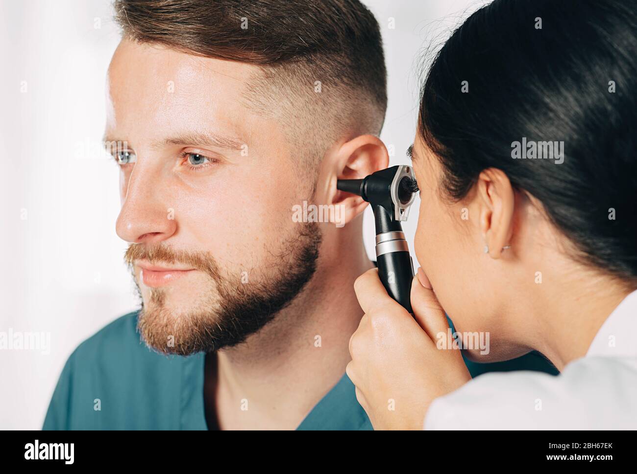 Mann bekommen medizinische Ohr Untersuchung in der Klinik. Audiologe Untersuchung des Ohrs des männlichen Patienten, mit Hilfe von Otoskop Stockfoto