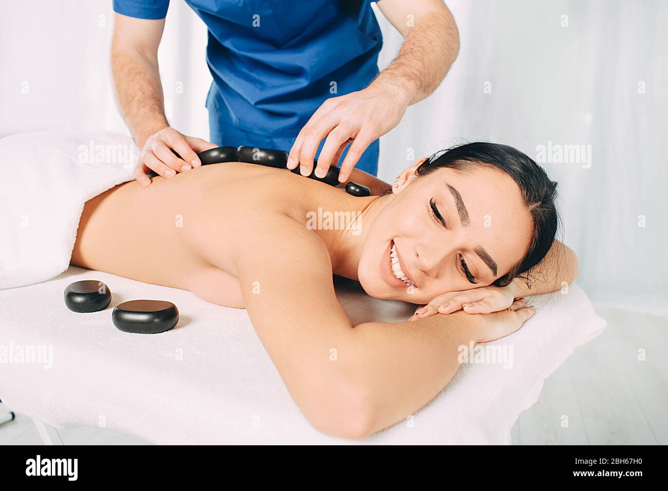 Entspannende Hot Stone Massage. Glückliche Frau, die im Spa-Resort eine Steinmassage bekommt Stockfoto