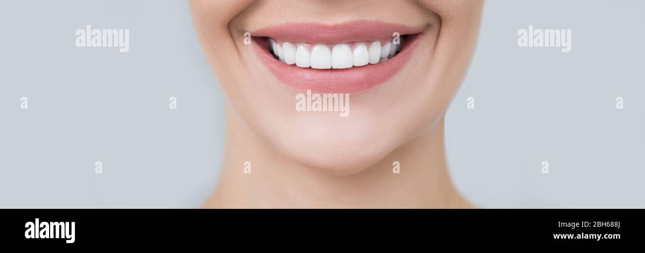 Perfektes weibliches Lächeln auf grauem Hintergrund. Gesunde weiße Zähne, Werbung Zahnmedizin Stockfoto