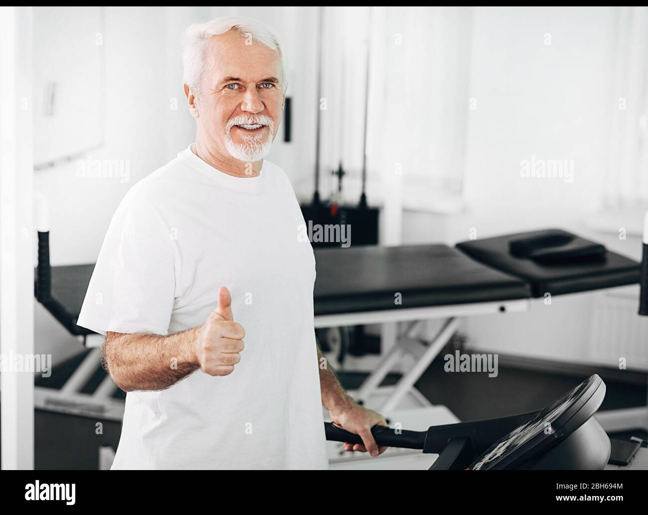 Der ältere Mann zeigte während des Trainings im Wellnesscenter die Daumen nach oben Stockfoto