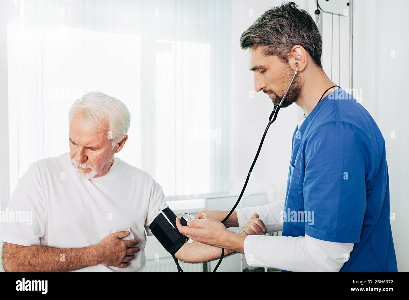 Hausarzt wird den Blutdruck an einem älteren Patienten messen. Ein älterer Mann leidet unter hohem Blutdruck, Bluthochdruck Stockfoto