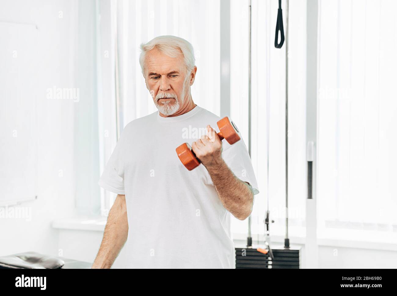 Senior Mann Heben Gewichte in einer Übung Klasse. Gesunde Lebensweise alte Menschen Stockfoto