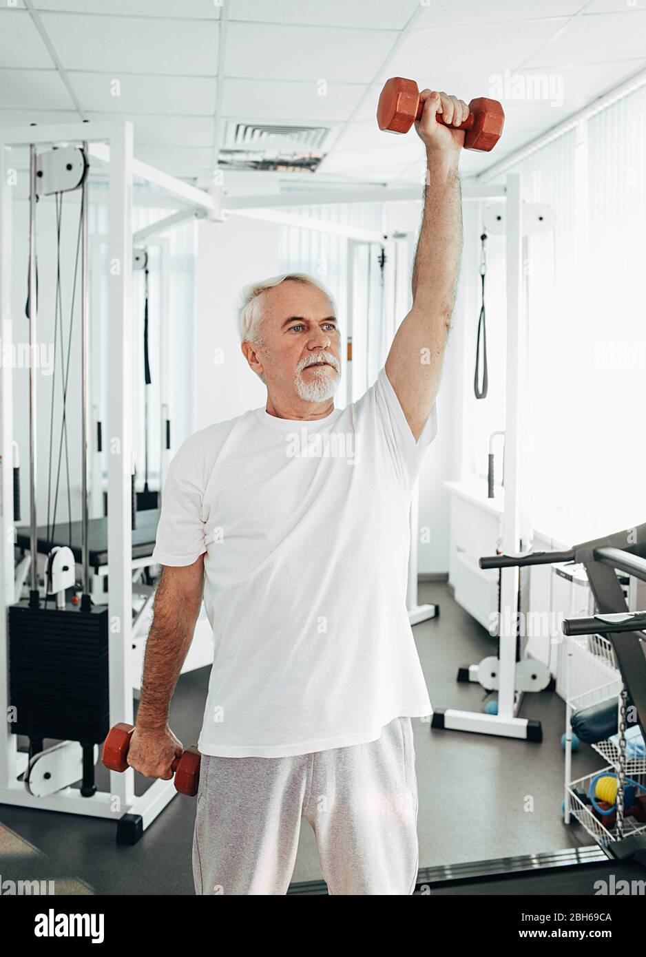 Senior Mann Heben Gewichte in einer Übung Klasse. Gesunde Lebensweise alte Menschen Stockfoto