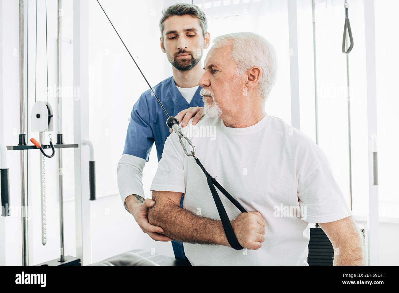 Senior Patient Ausbildung mit seinem Kinesiotherapeuten, Erholung mit speziellen Übungen. Gemeinsame Behandlung, Kinesiotherapie Stockfoto
