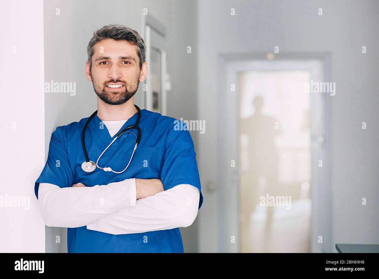Männlicher Physiotherapeut mit Stethoskop in der Klinik. Er lächelt und schaut auf die Kamera. Stockfoto