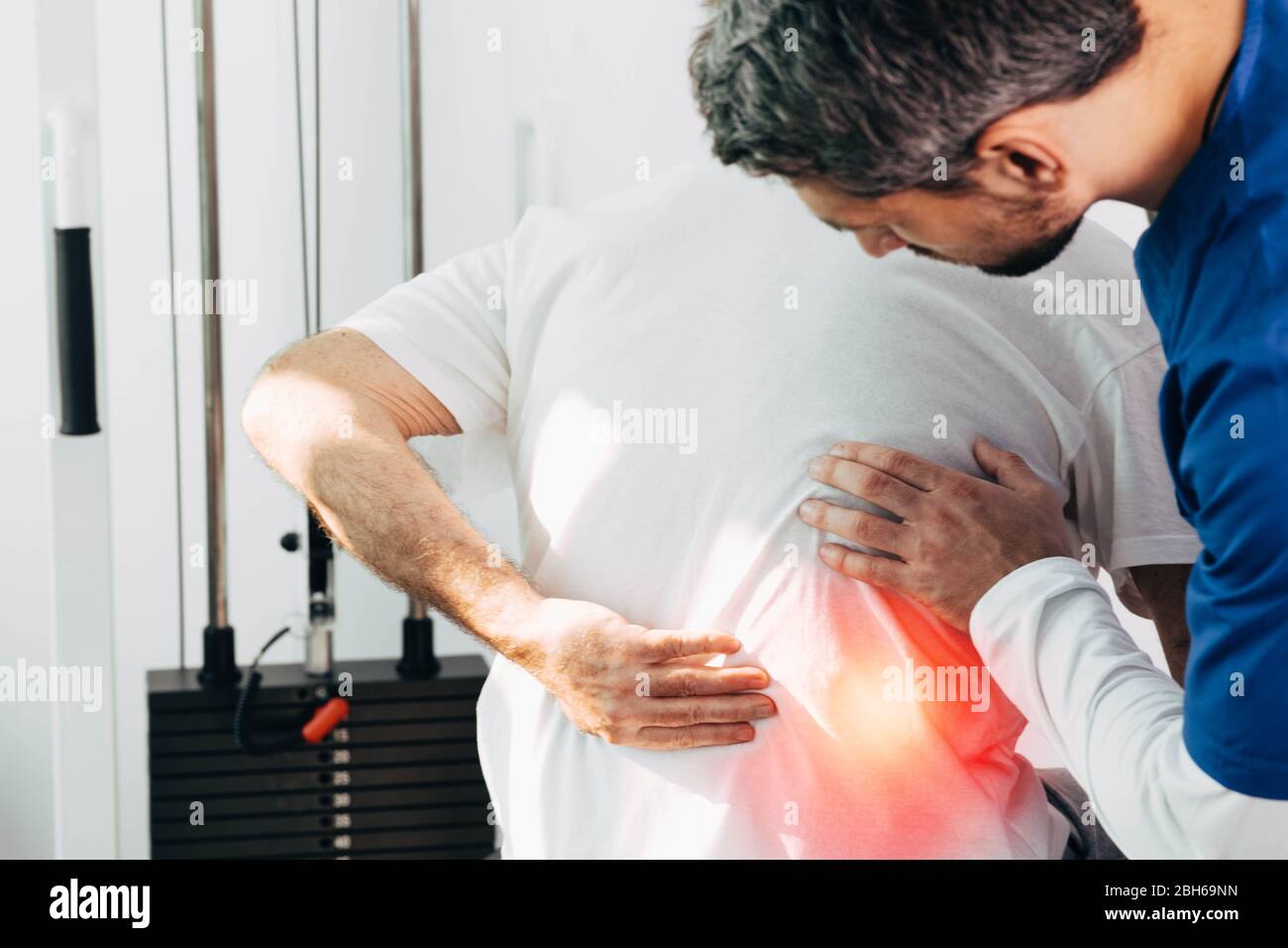 Physiotherapeut untersucht Senior Patienten mit Rückenschmerzen. Rückenschmerzen und Hexenschuss Stockfoto