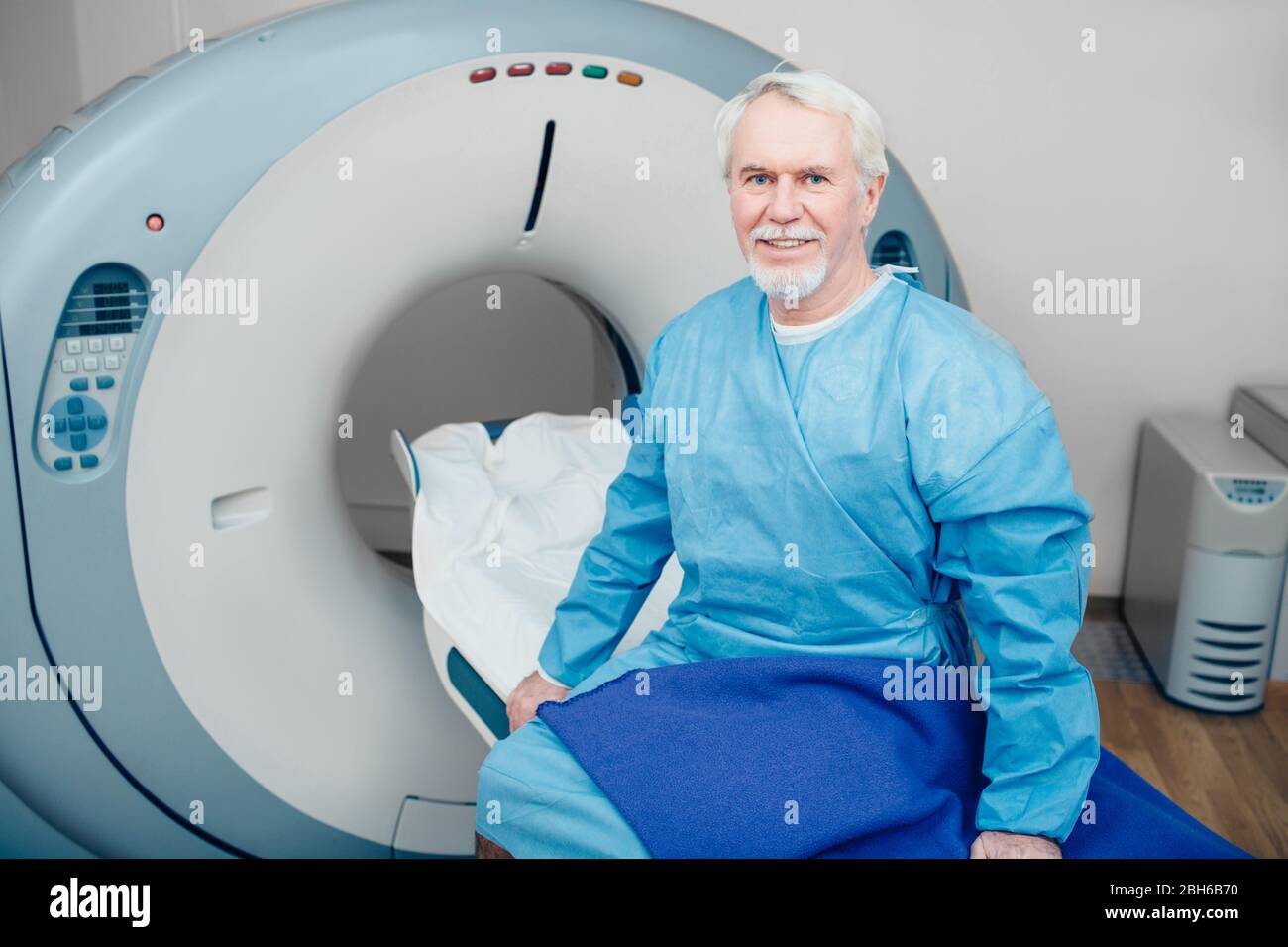 Älterer Mann sitzt auf Scanner Tabelle. Warten auf CT-Scan Stockfoto