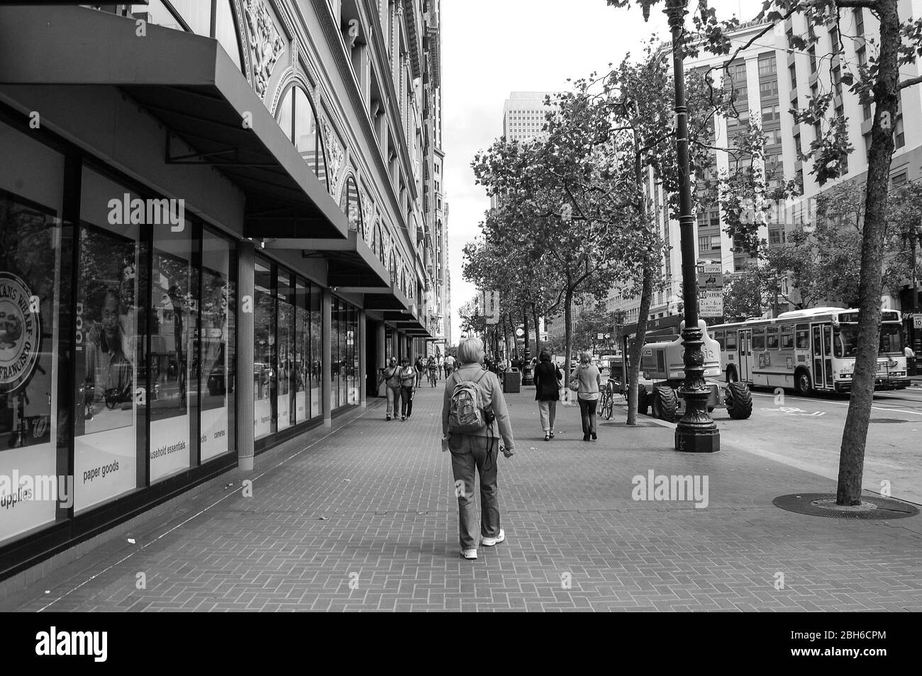 Blonde Geschäfte in San Francisco Walking Girl Läden Bäume Fußweg Bäume Läden Rucksack Leute beschildern Bogenblick Lichter Bus Stockfoto