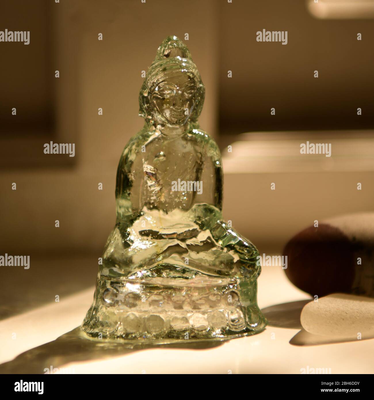 Kleiner Glas Buddha auf sonniger Fensterbank Stockfoto