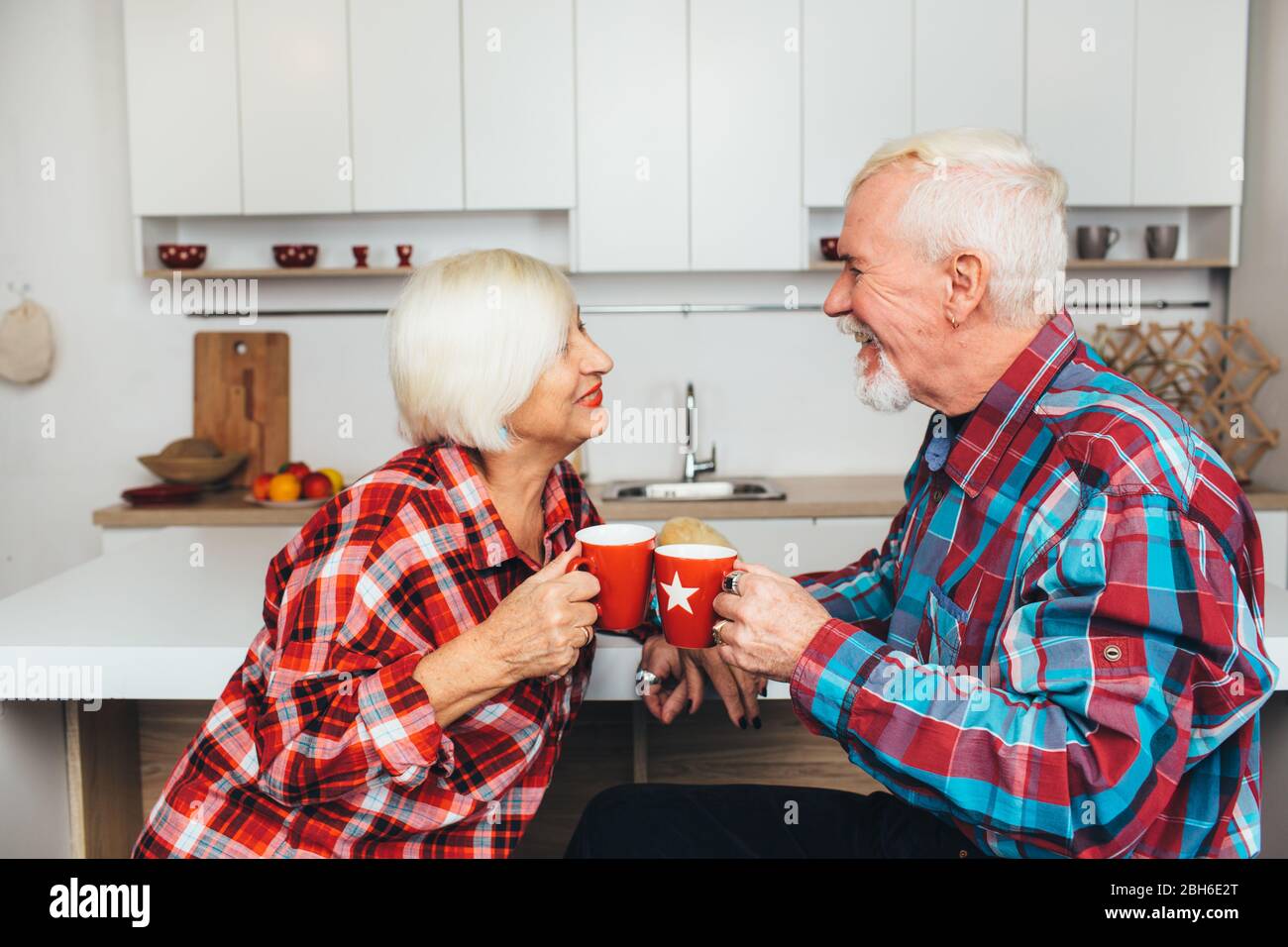 Frühstück mit einem geliebten Menschen, ältere Männer und Frauen trinken zusammen Latte, zu Hause in der Küche Stockfoto