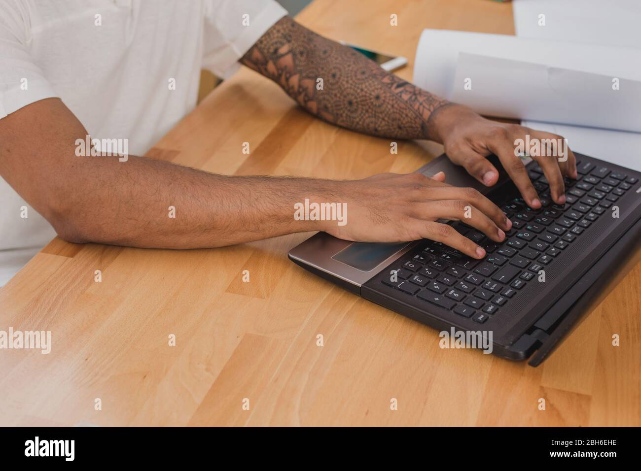 Männerhände mit Tätowierungs-Nahaufnahme, Tippen auf Laptop-Tastatur. Stockfoto