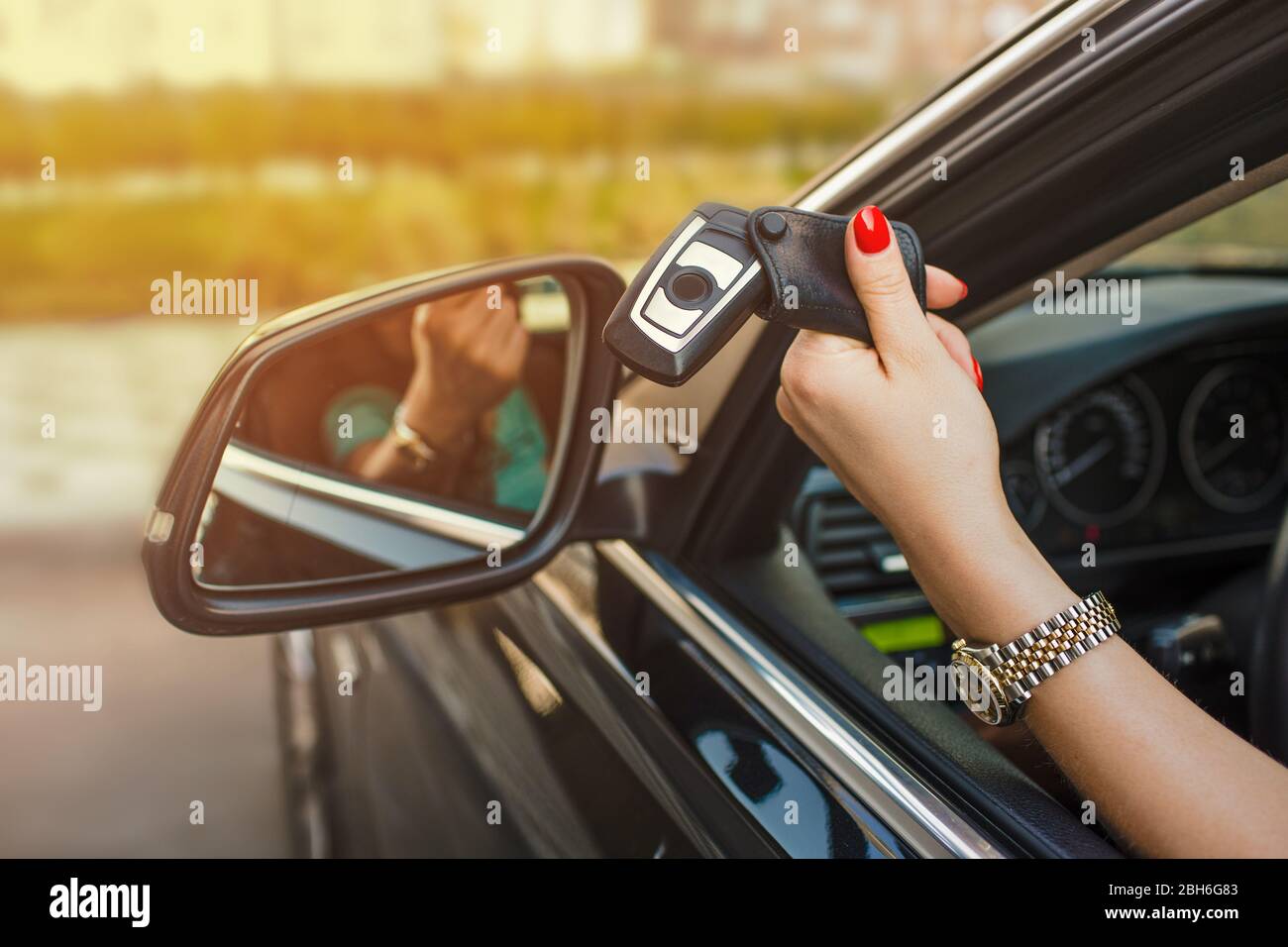 Weibliche Hand hält Autoschlüssel aus dem Autofenster Stockfoto