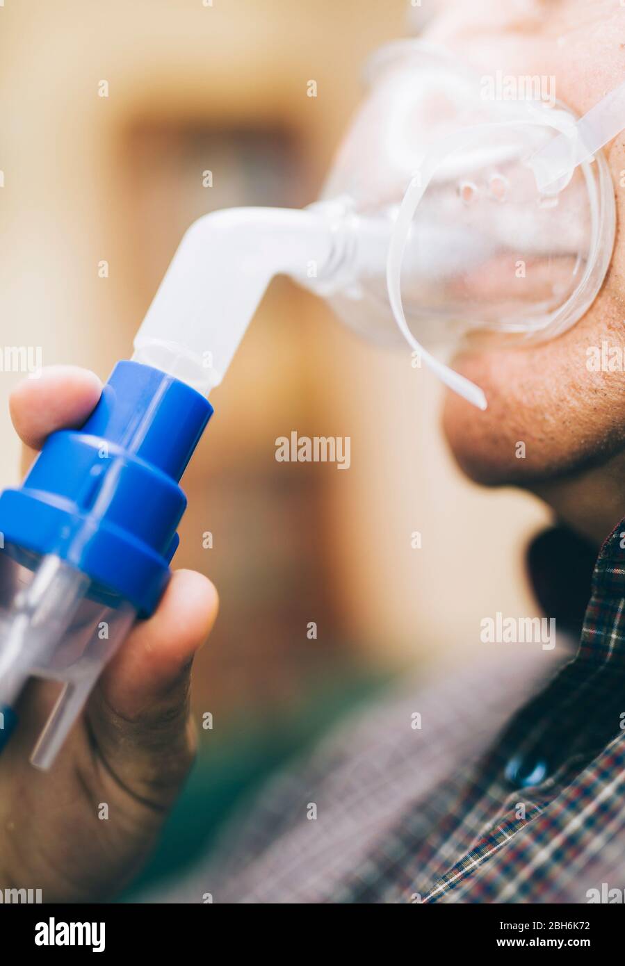 Leitender Mann, der medizinische Geräte für die Inhalation mit Atemschutzmaske verwendet, Vernebler im Zimmer Stockfoto